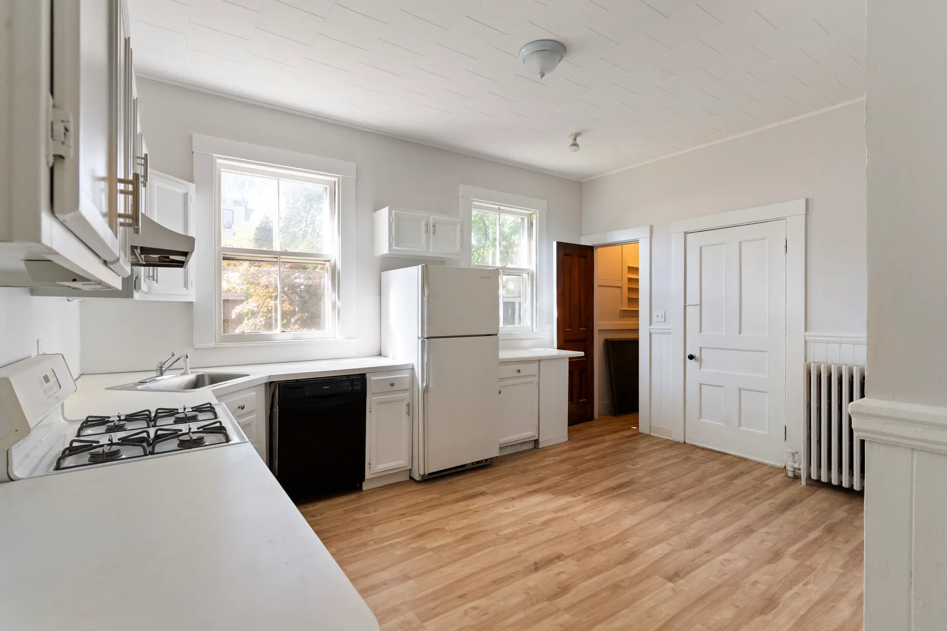 Existing kitchen at 62 Fuller Street with white cabinets, an older range, and two tall windows before renovation